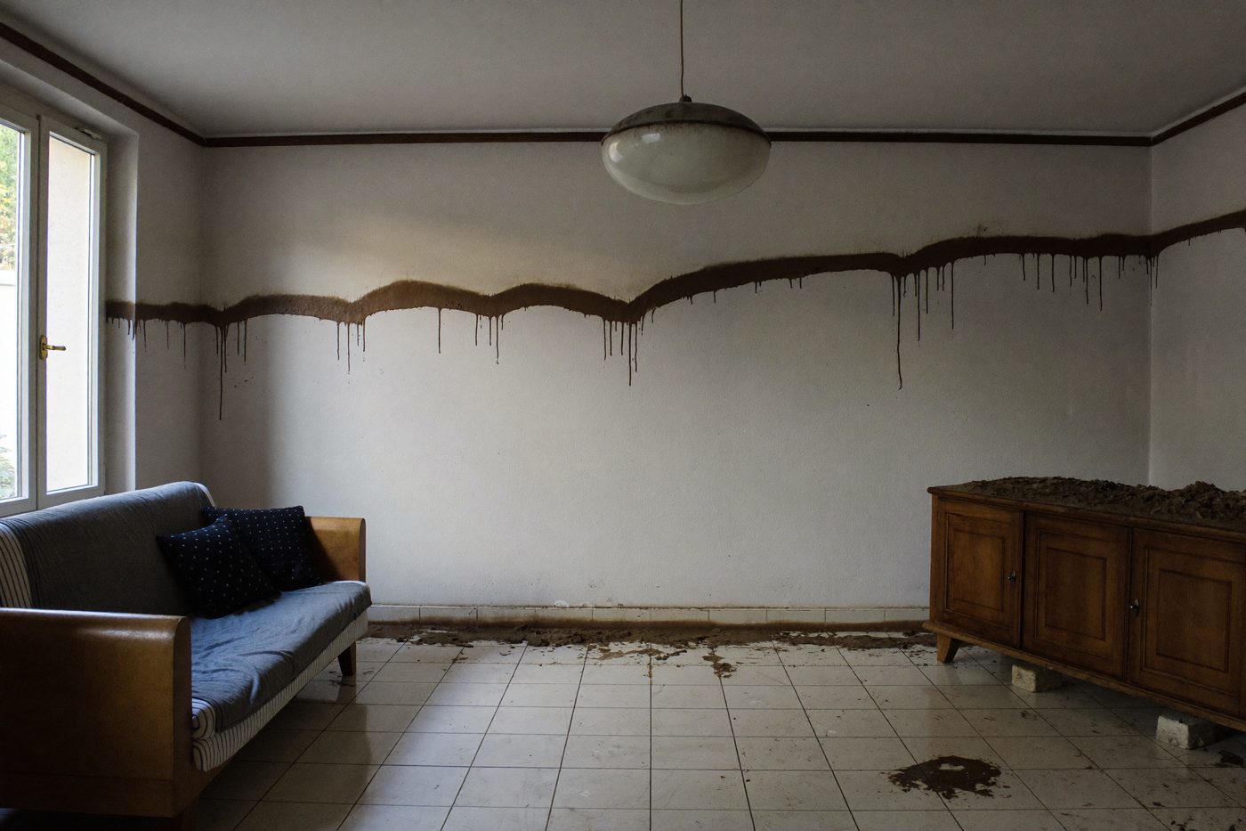 Salon après la décrue, ligne d'eau visible sur le mur — illustration